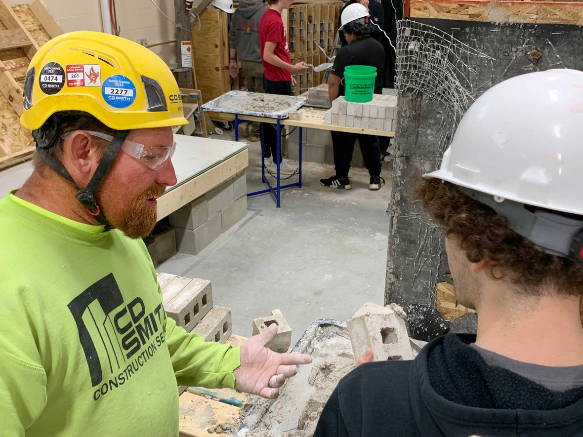 02 CD Smith Construction mason teaches Fond du Lac high school student how to butter bricks at Masonry Week event IMG_4134