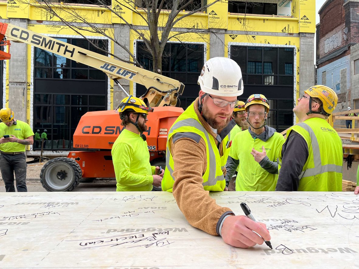 CD Smith Construction Project Manager Brett Jerdee signs CLT for Bakers Place mass timber building topping out in Madison Wisconsin