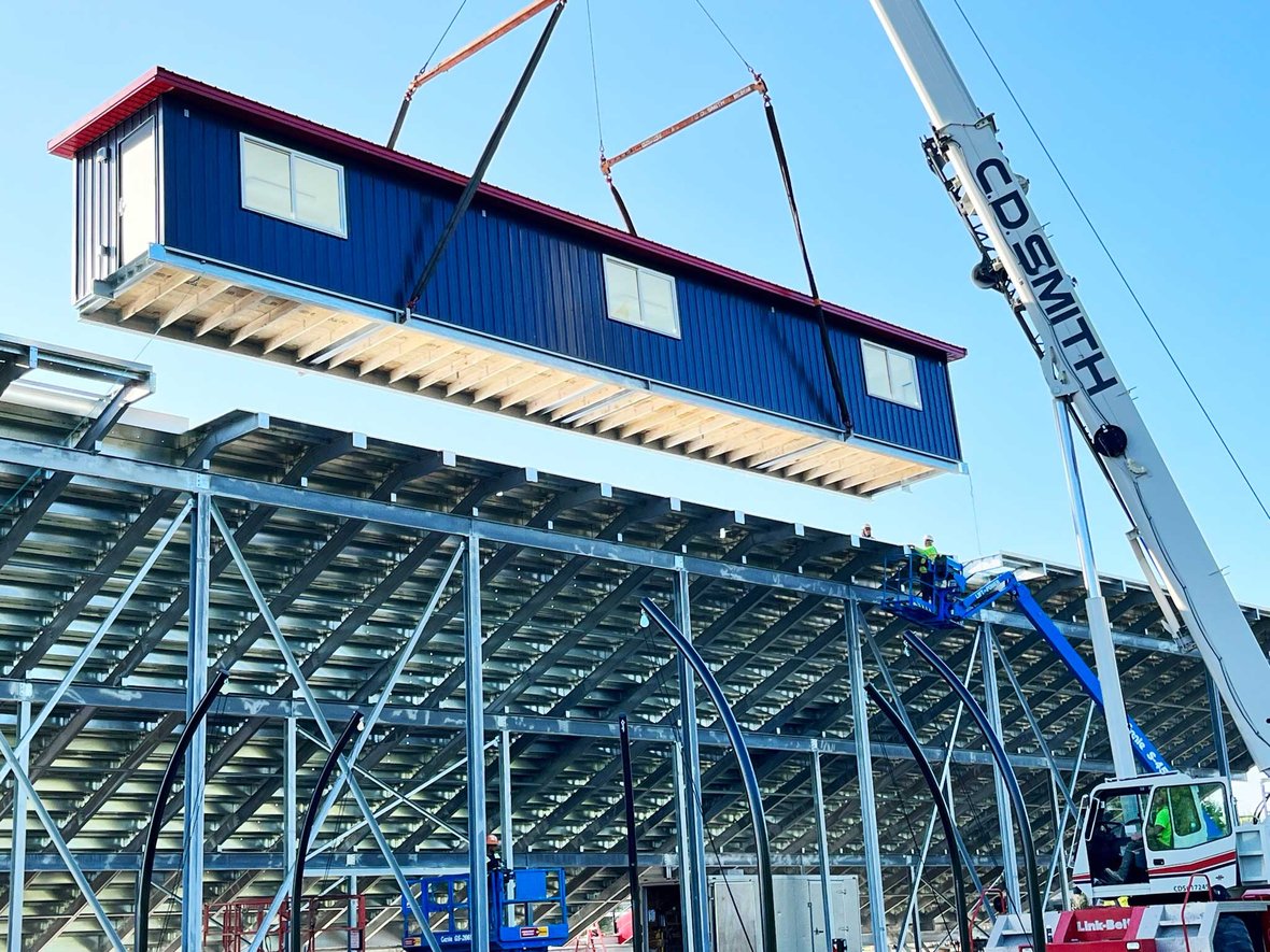 Fond du Lac School District Cardinal Stadium view of press box installation using crane to lift on bleachers built by CD Smith Construction in Wisconsin