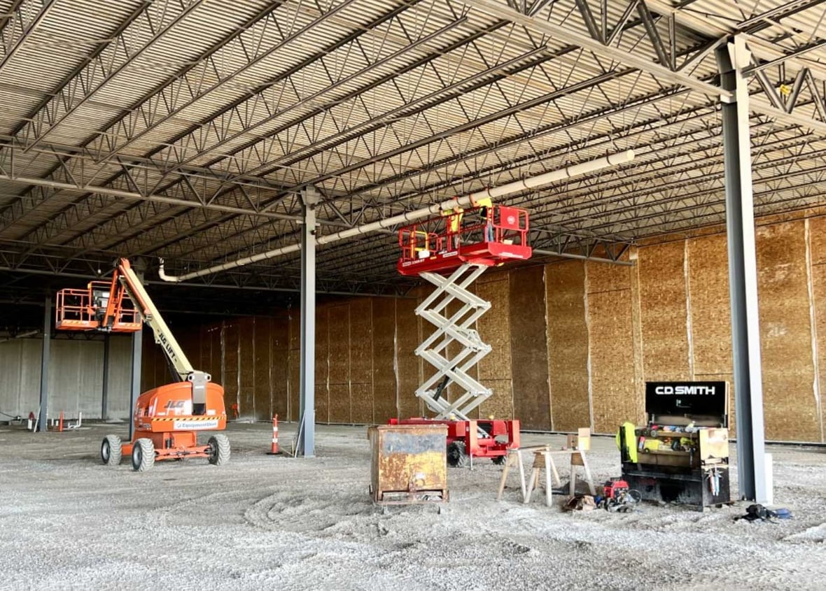 C.D. Smith Construction workers use a lift for installing pipe on the interior ceiling of Kondex Corporation manufacturing addition