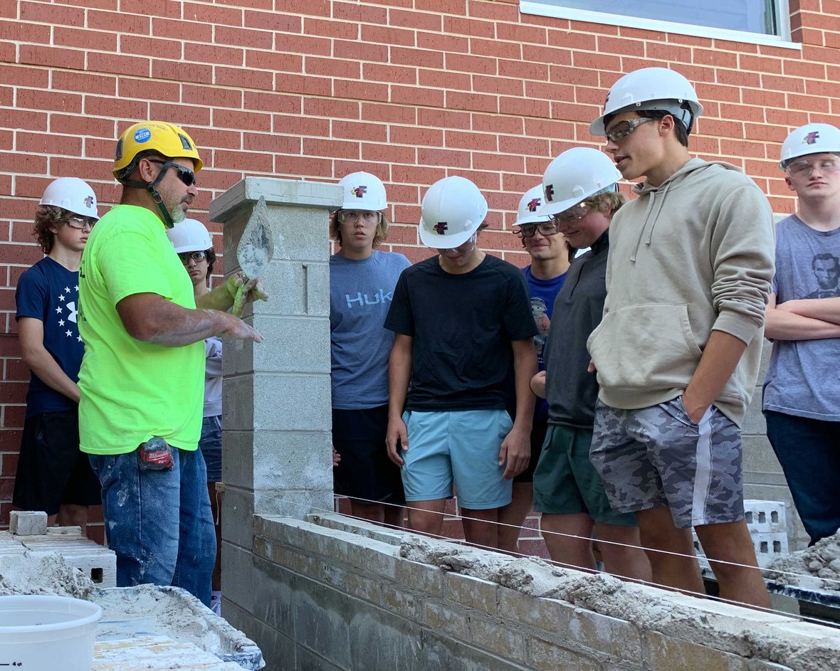 C.D. Smith mason Mark Hau showing Fond du Lac High School students hands-on bricklaying techniques