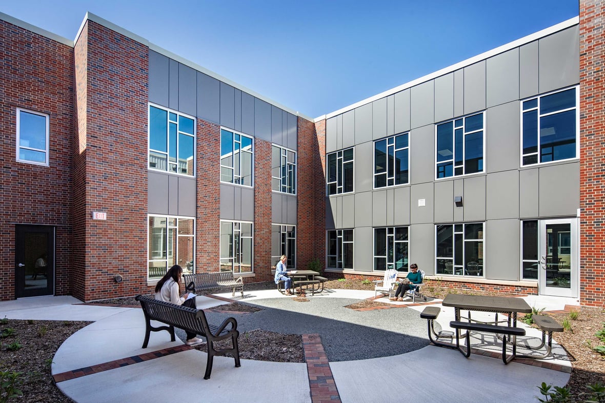 Outdoor courtyard area adjacent to the Kohler School District library, featuring individuals reading and enjoying the fresh air in a beautifully landscaped space designed for community engagement.