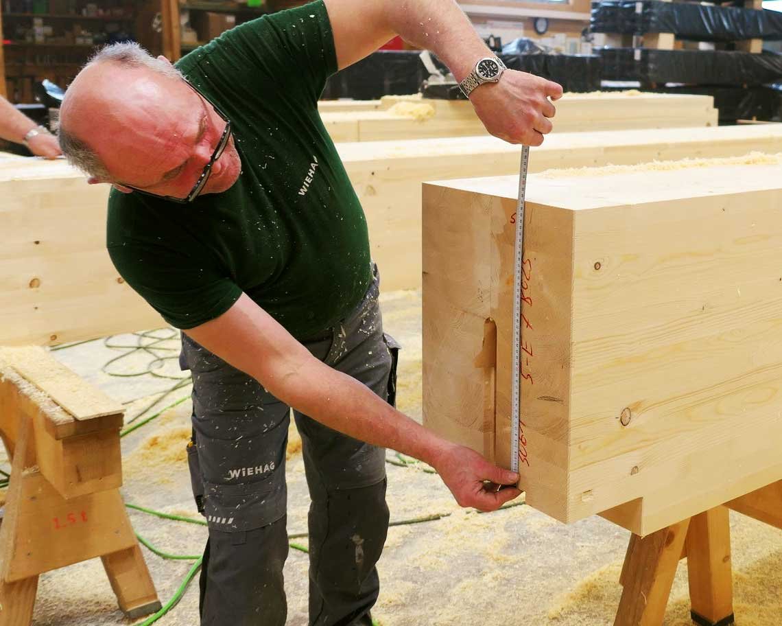Worker measuring mass timber columns and glue-laminated beams prefabricated offsite for Ascent mass timber construction