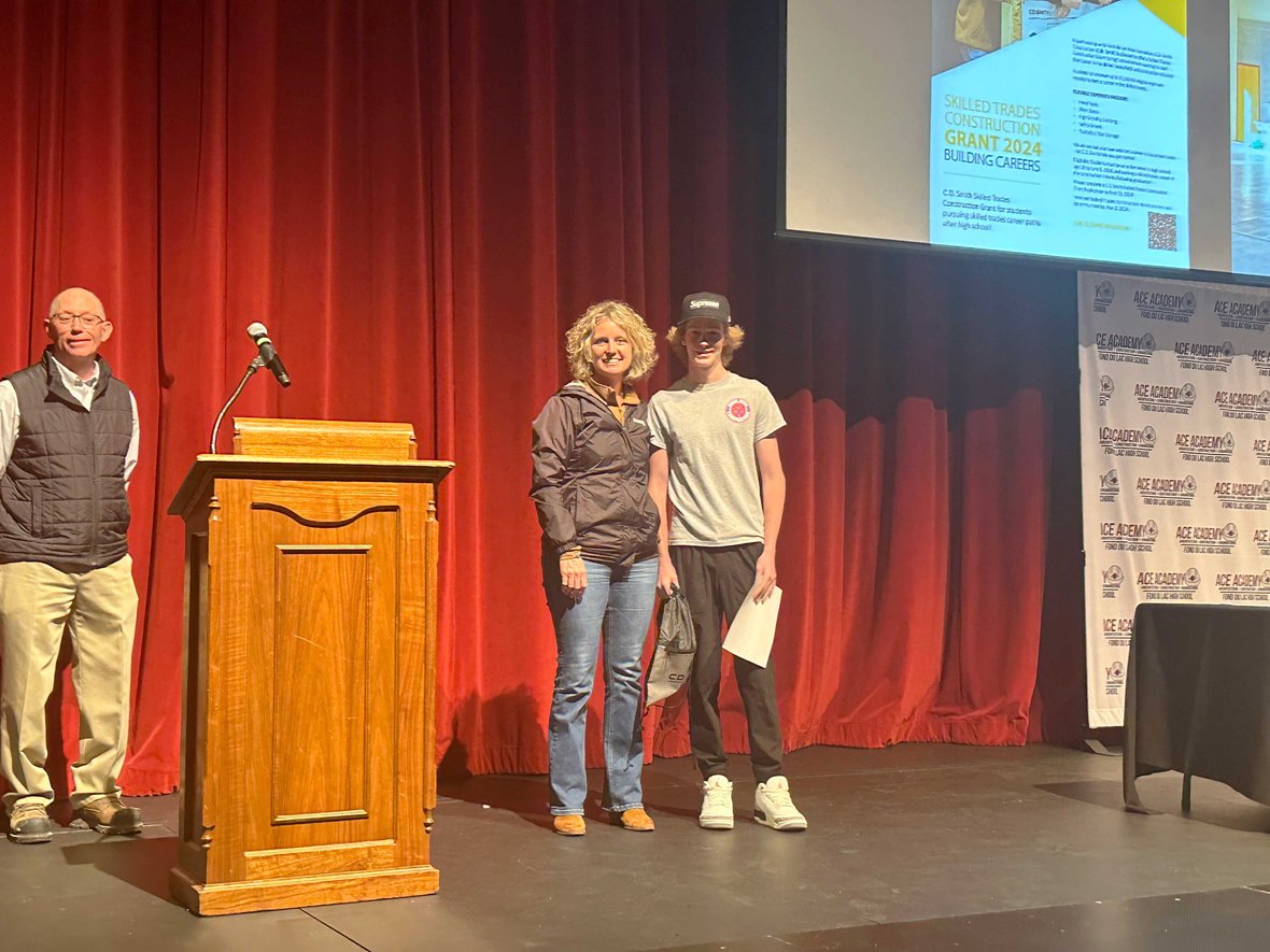 Connie Coon recognizes ACE Academy Student Mason Forster for winning the 2024 CD Smith Skilled Trades Grant on stage at FDL High School in Wisconsin