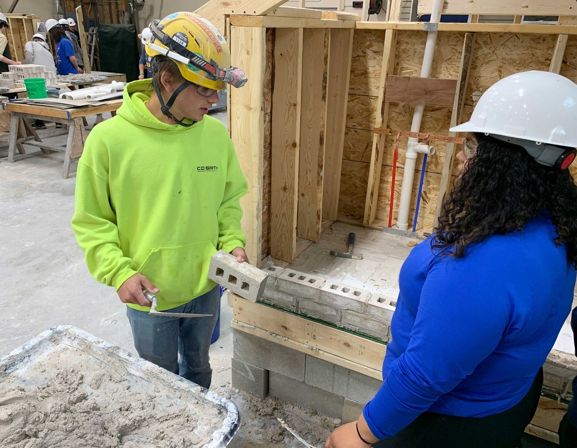 05 CD Smith mason teaches Fond du Lac high school student how to butter bricks at Masonry Week event IMG_4144