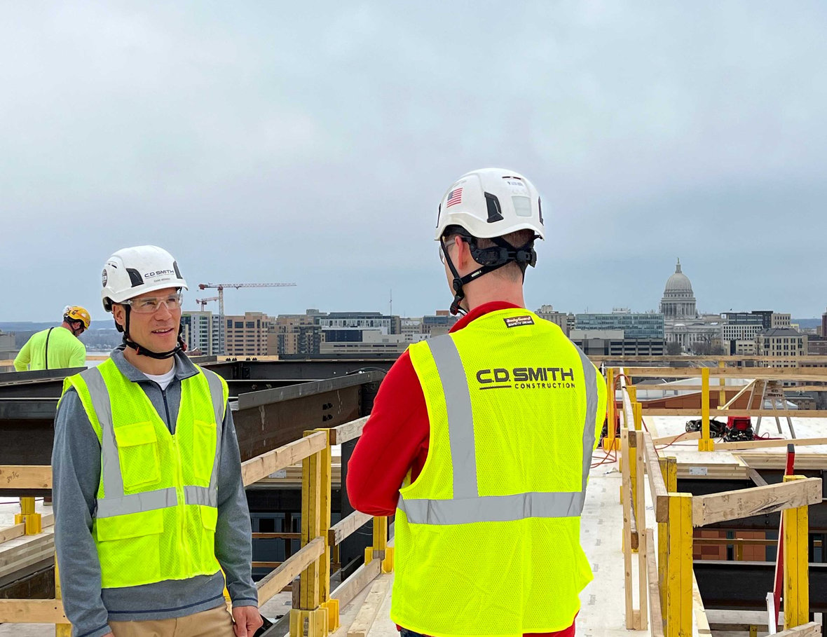 CD Smith Construction Project Managers on top floor of Bakers Place mass timber building with view of capital and cranes in the background in Madison Wisconsin