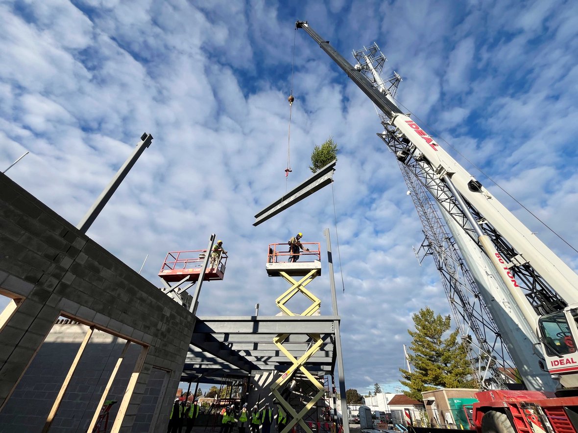 CD Smith Construction crews hoist flying beam on crane for ironworkers at topping out of Kewaskum COmmunity Center in Wisconsin
