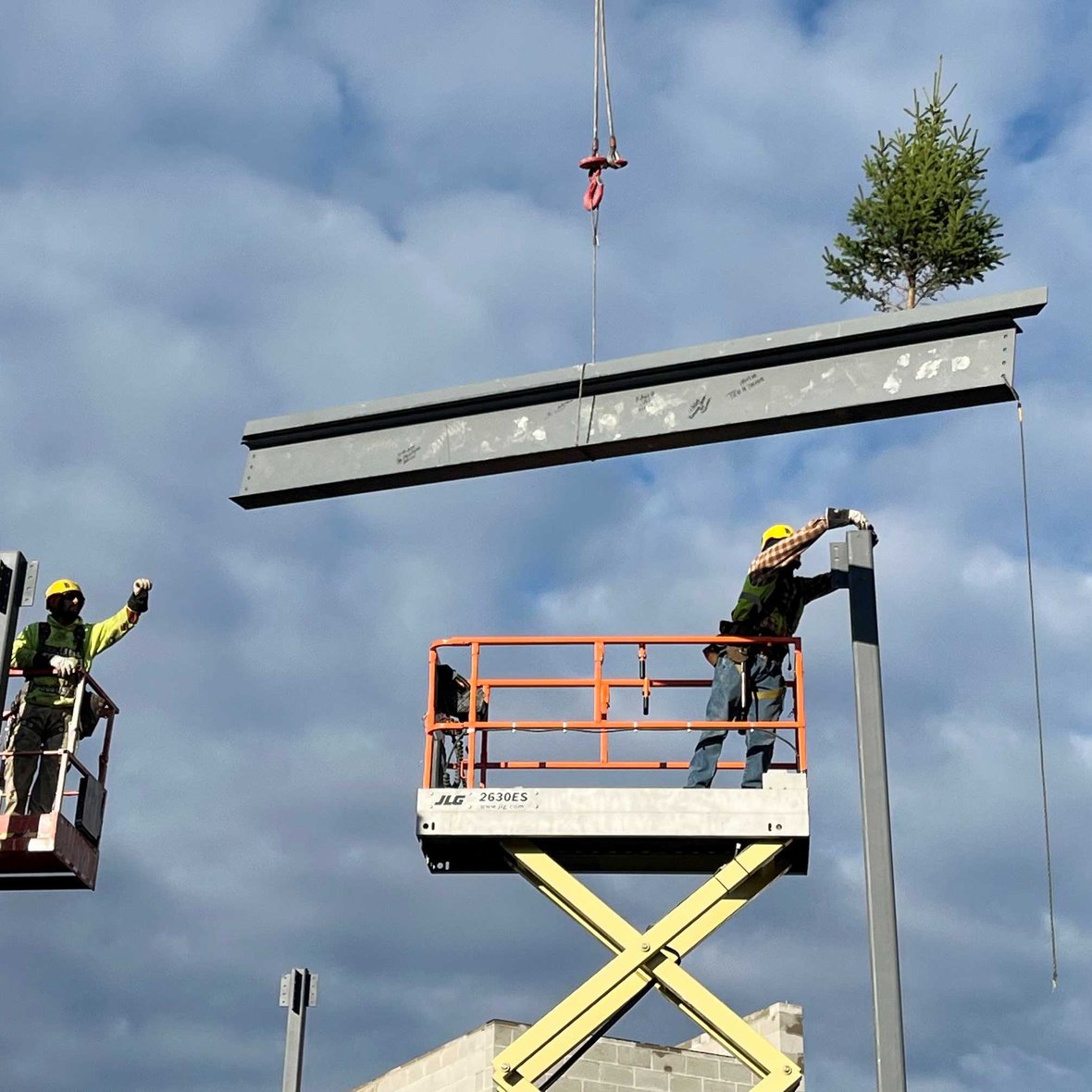 CD Smith Construction crews hoist flying beam on crane for ironworkers at topping out of Kewaskum COmmunity Center in Wisconsin
