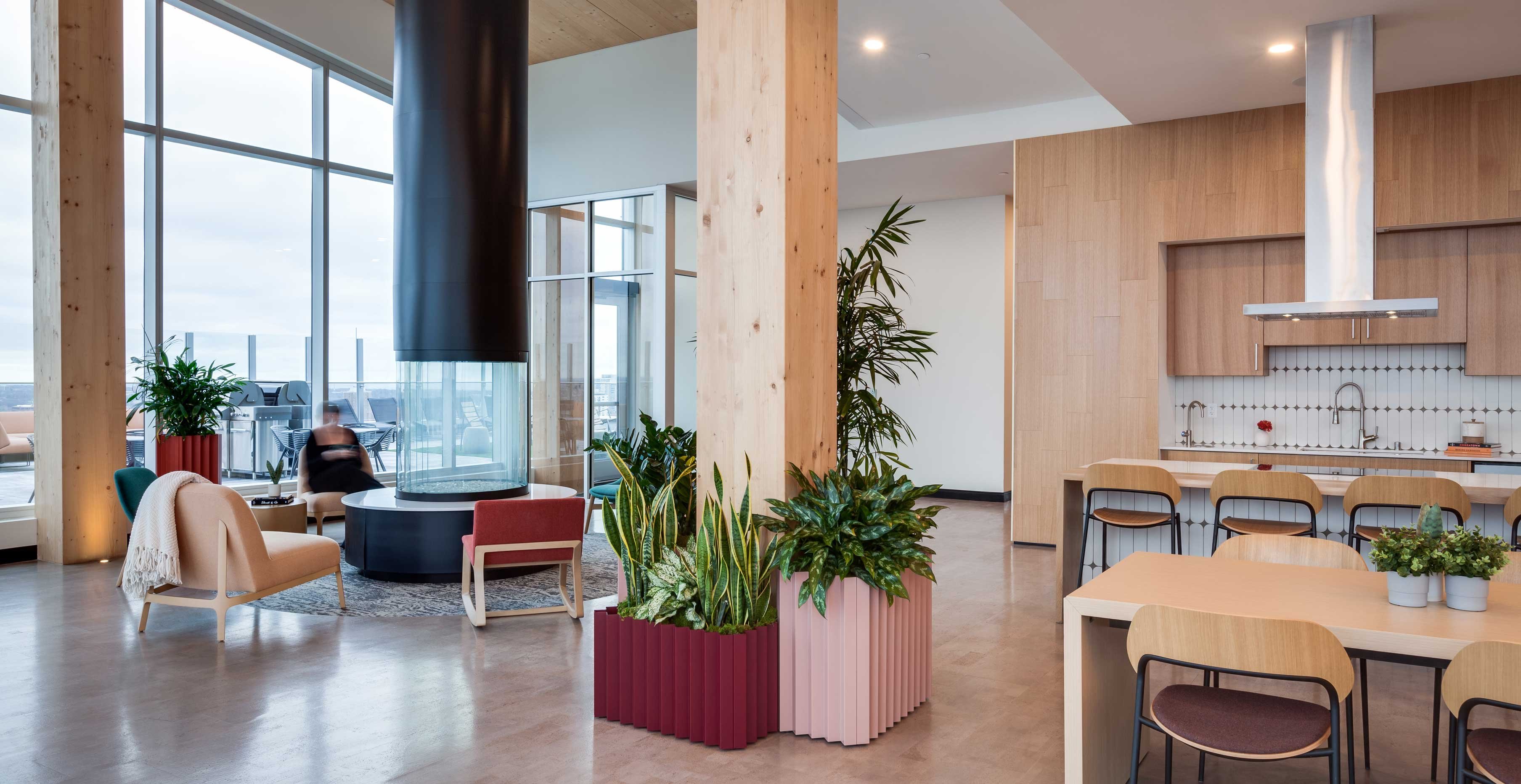 Mass timber community lounge at Ascent featuring central glass fireplace, exposed timber columns, and floor to ceiling windows.