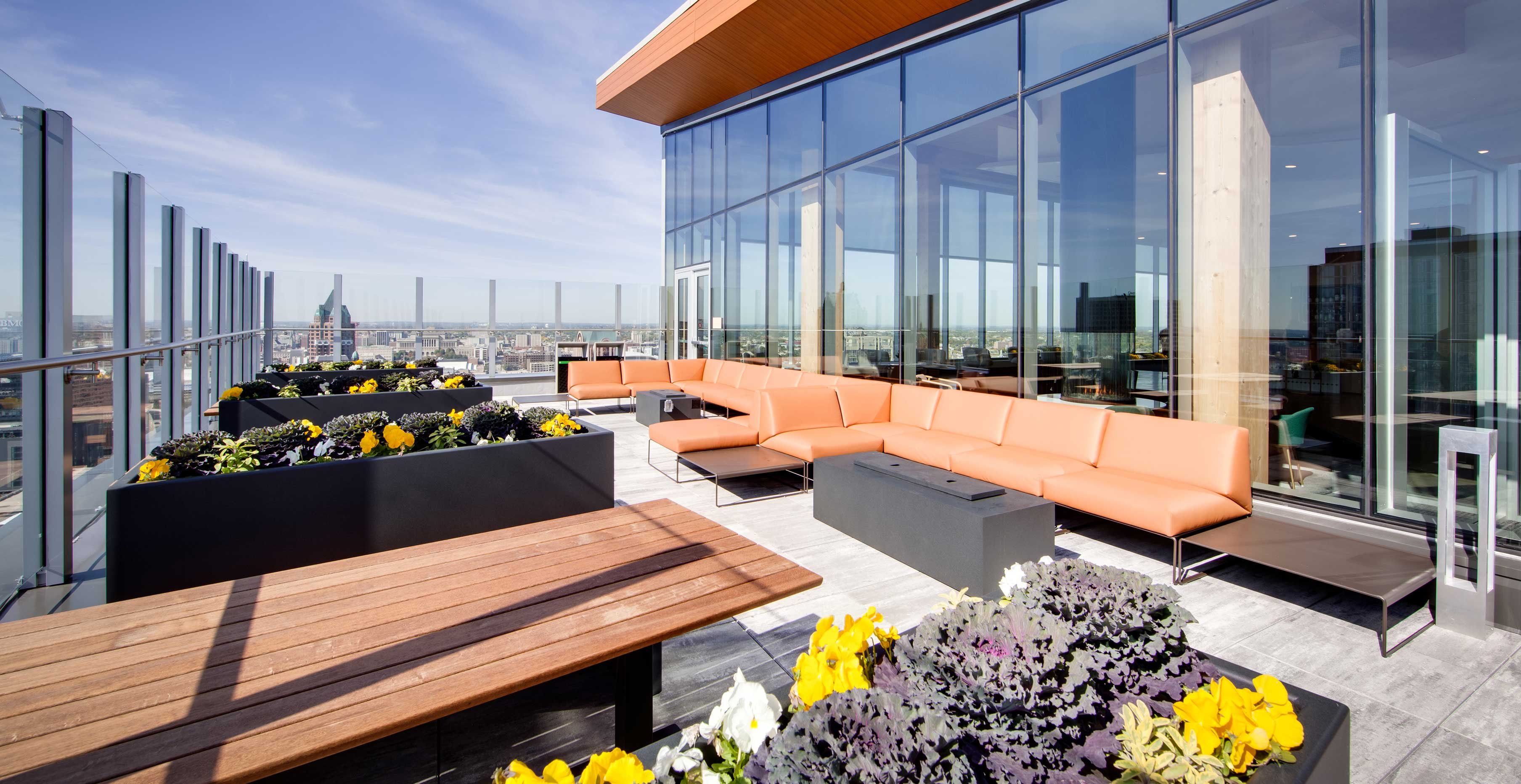 Outdoor terrace at Ascent in Milwaukee featuring rooftop seating, planters, and views of downtown skyline.