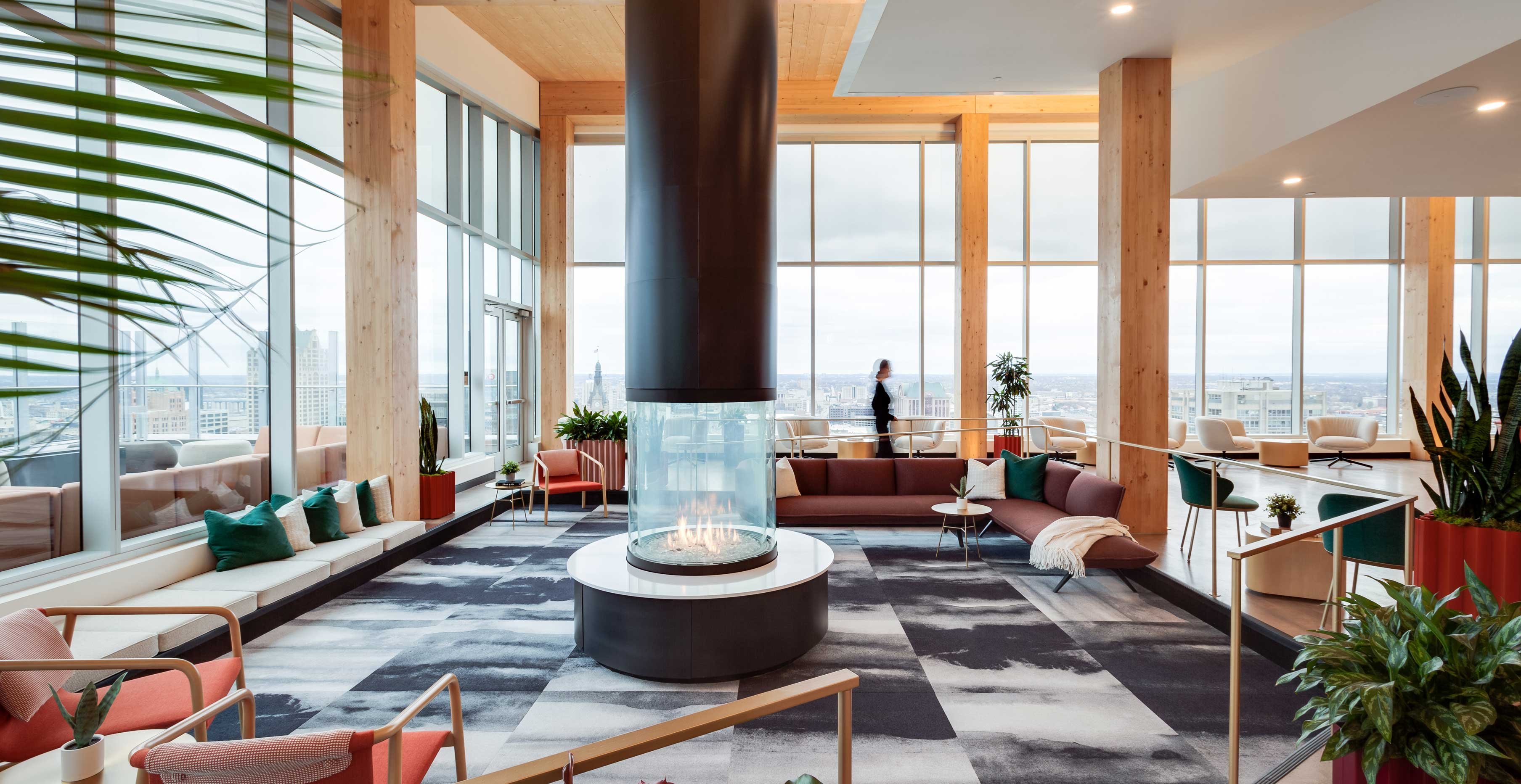 25th floor amenity lounge at Ascent Milwaukee featuring sunken seating area, exposed timber columns, and central fireplace.