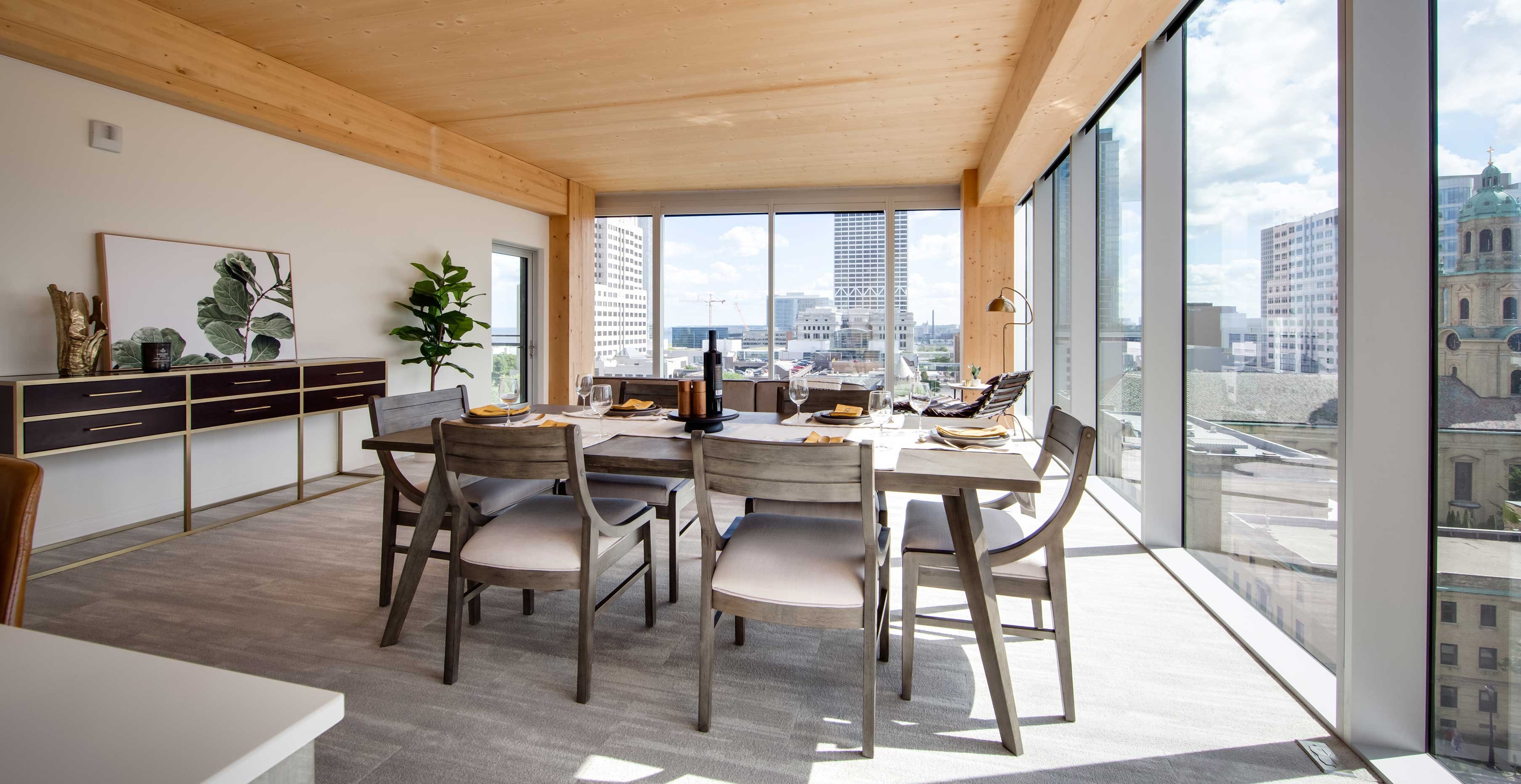Modern dining space at Ascent Milwaukee highlighting structural mass timber ceiling and urban skyline backdrop.