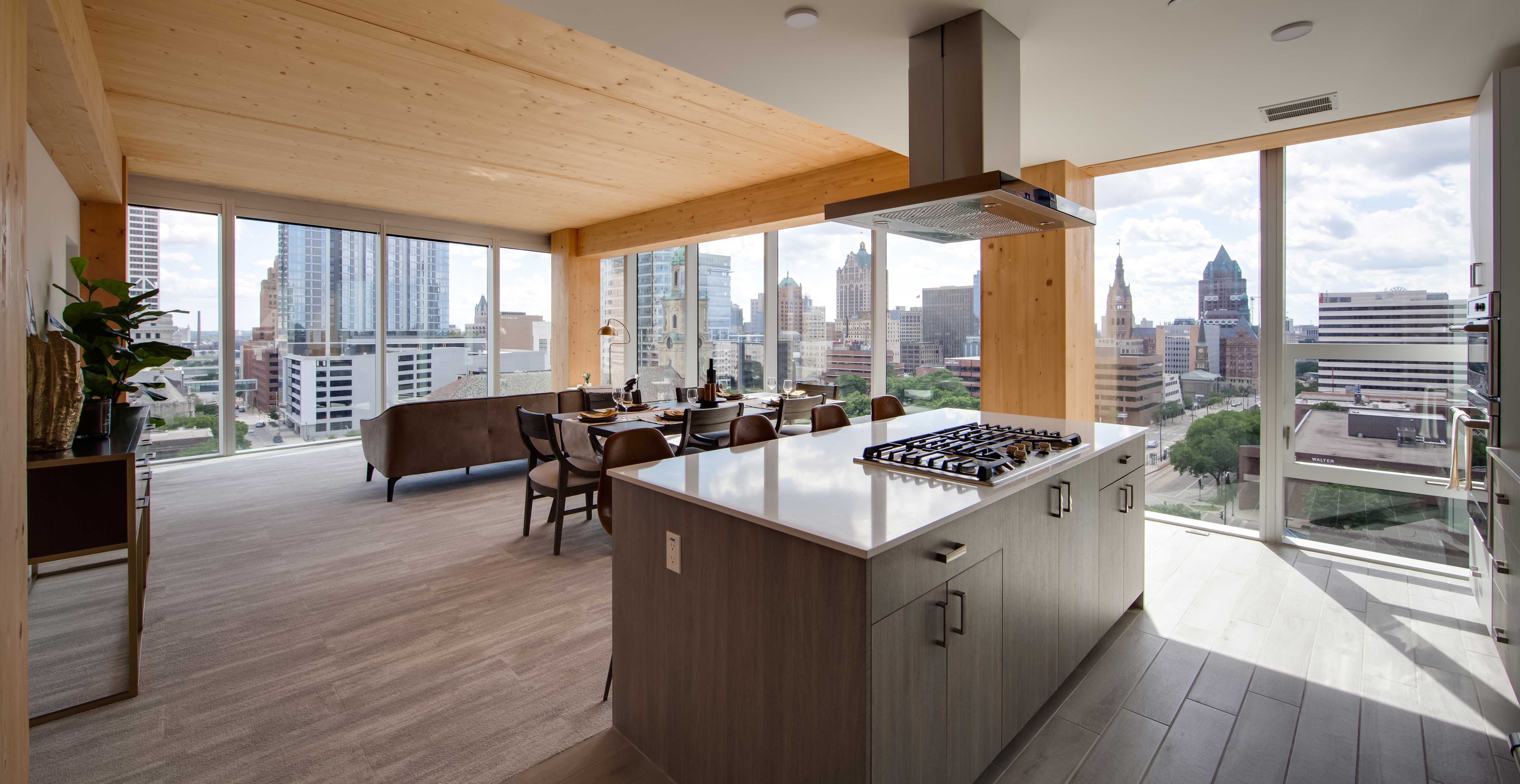 Open concept kitchen at Ascent Milwaukee with exposed timber beams, quartz island, and panoramic city views.