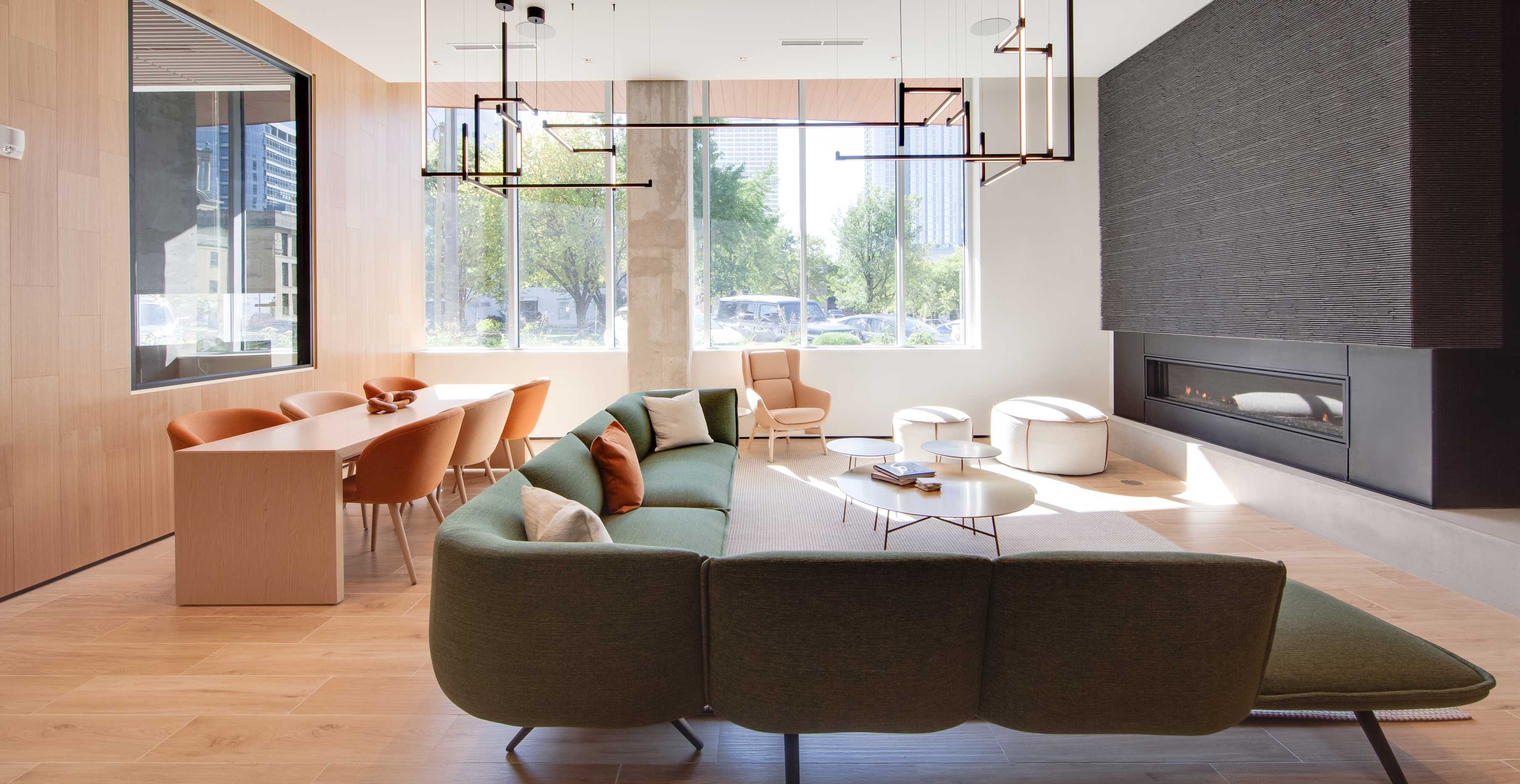 Modern entry lobby at Ascent in Milwaukee featuring exposed mass timber columns, double height glass curtainwall, and contemporary seating.