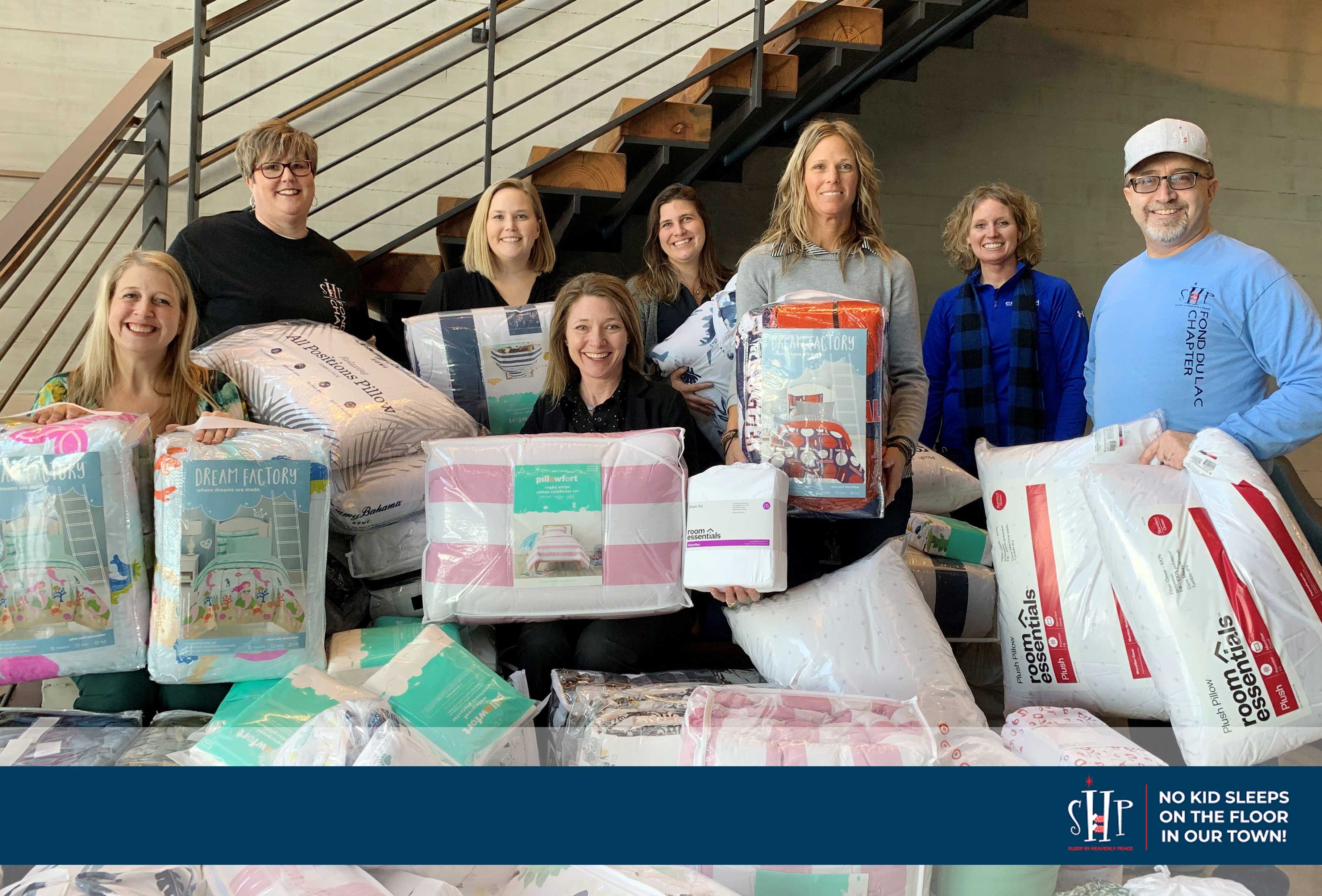 C.D. Smith Construction team at Fond du Lac Corporate Office with bedding donation for SHP Bed Build recipients