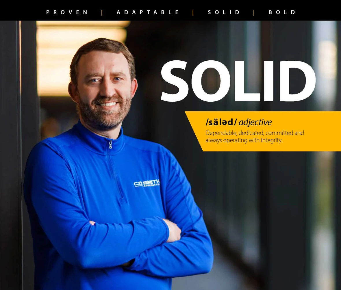 CD Smith Construction Chief Financial Officer leaning on a steel beam with SOLID text in the foreground with a definition of it as a company value
