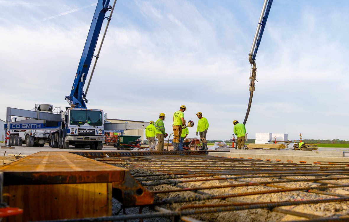CD Smith Construction Concrete Crew with Cement Truck in background and Rebar Jobsite Prep in Foreground