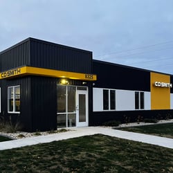 Exterior view of C.D. Smith Construction's Milwaukee office at dusk, seen from Tower Avenue, with the building illuminated against the evening sky