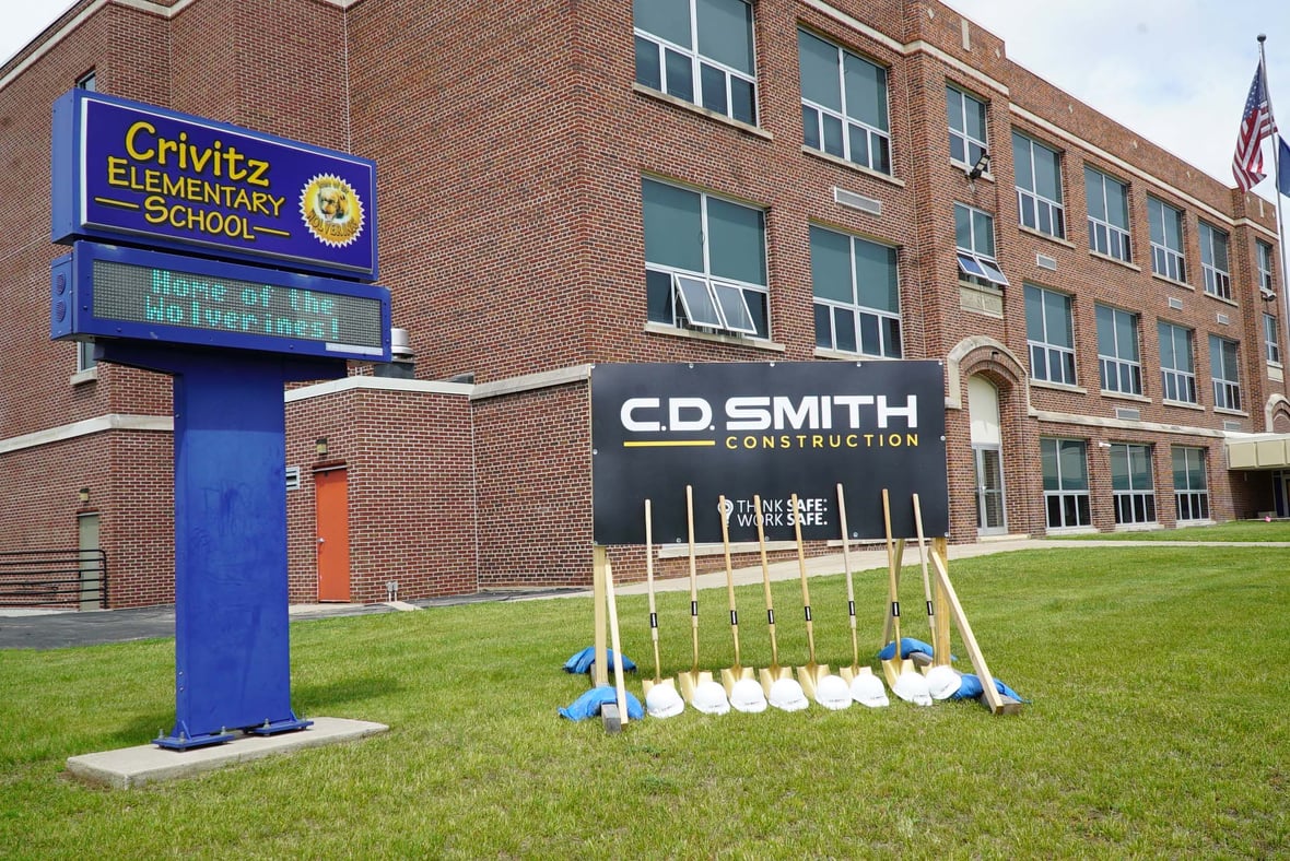 Groundbreaking ceremony at Crivitz Elementary School with ceremonial shovels and C.D. Smith Construction sign in front of the historic school building in Wisconsin