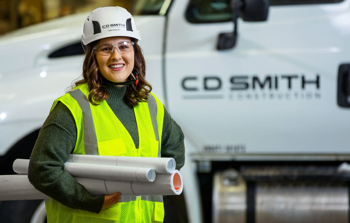 C.D. Smith Construction Project Manager Sara Wright holding drawings in front of C.D. Smith logo truck