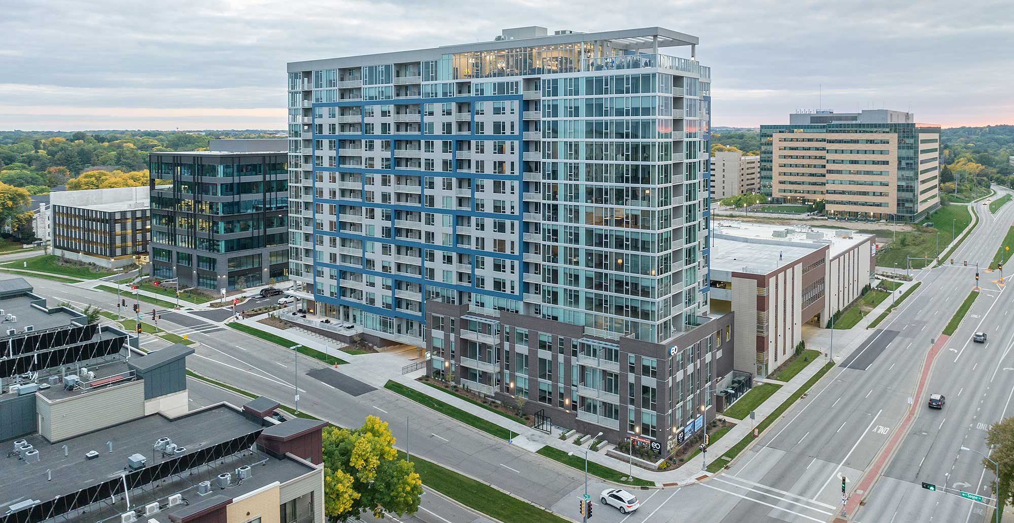 Madison Yards residential tower with glass façade and rooftop terrace, located in the Hill Farms neighborhood of Madison, Wisconsin.