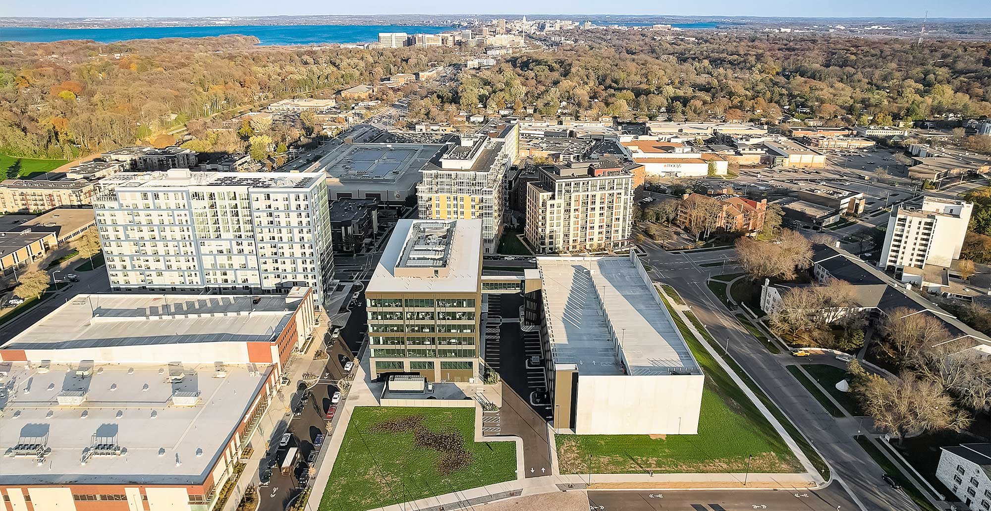 Drone view of Madison Yards development highlighting residential tower, office buildings, structured parking, and nearby city infrastructure.
