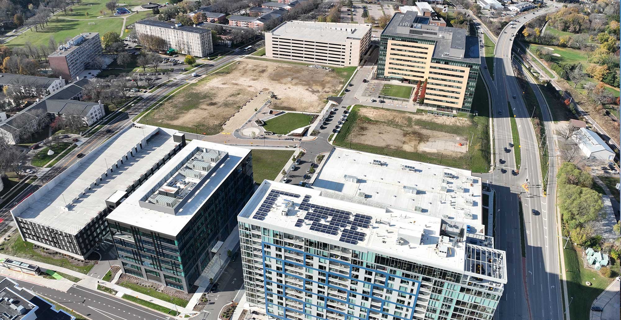 Aerial view of Madison Yards at Hill Farms showing residential buildings, structured parking, office space, and surrounding Madison landscape.
