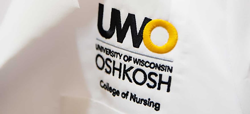 Nursing coat with close-up view of UWO University of Wisconsin-Oshkosh College of Nursing embroidery