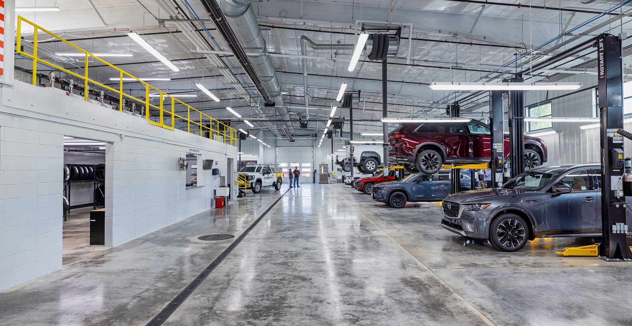 Interior view of Holiday Automotive Reconditioning Tech Center showing expanded service lanes, mezzanine storage and vehicle lifts within the newly constructed automotive facility.