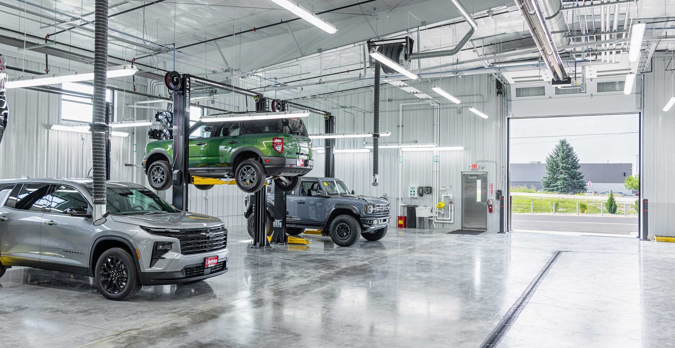 Automotive service bays at Holiday Automotive Reconditioning Tech Center with overhead doors, vehicle lifts and polished concrete floors.