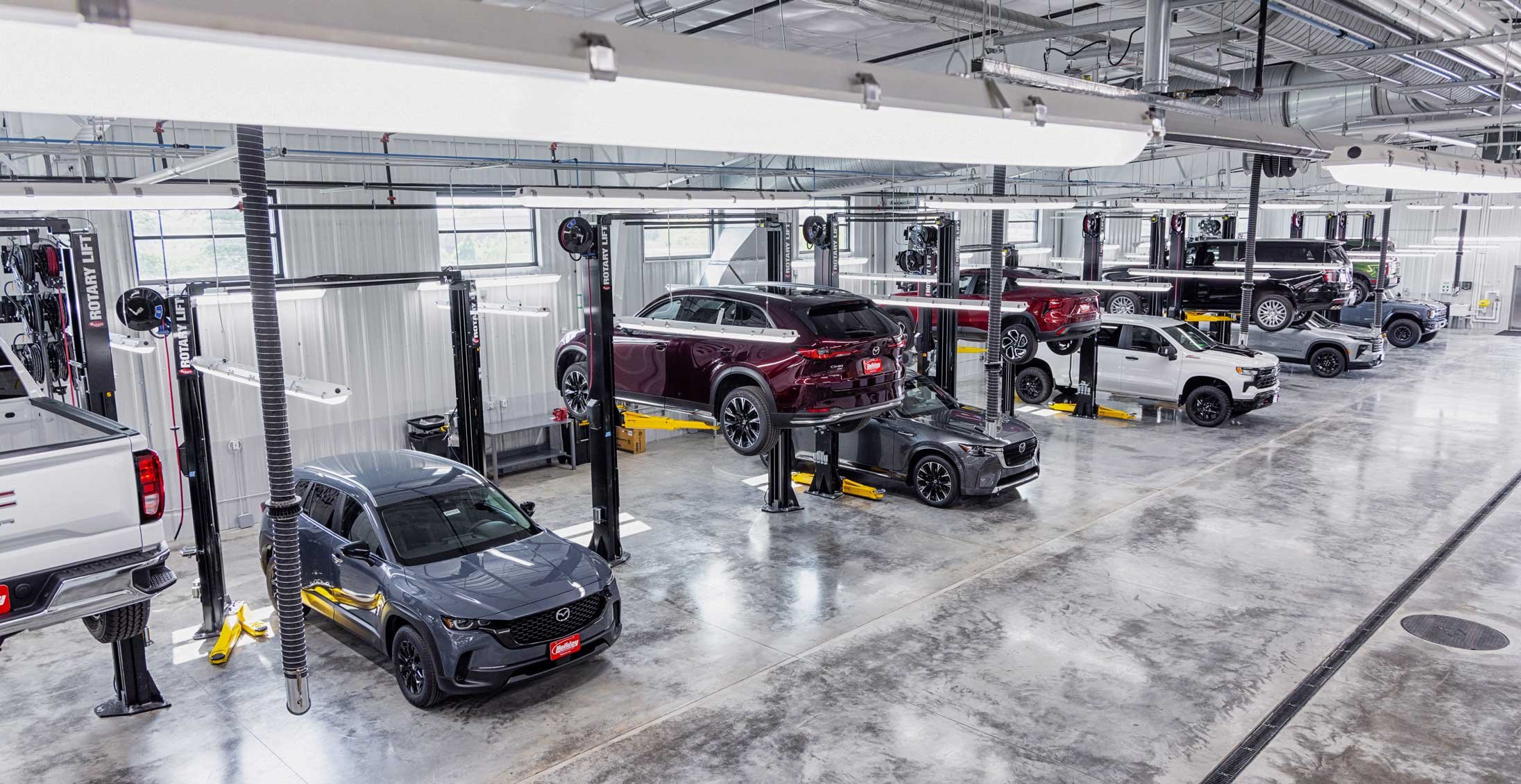 High-capacity vehicle reconditioning floor at Holiday Automotive featuring multiple service lifts and energy-efficient lighting systems.