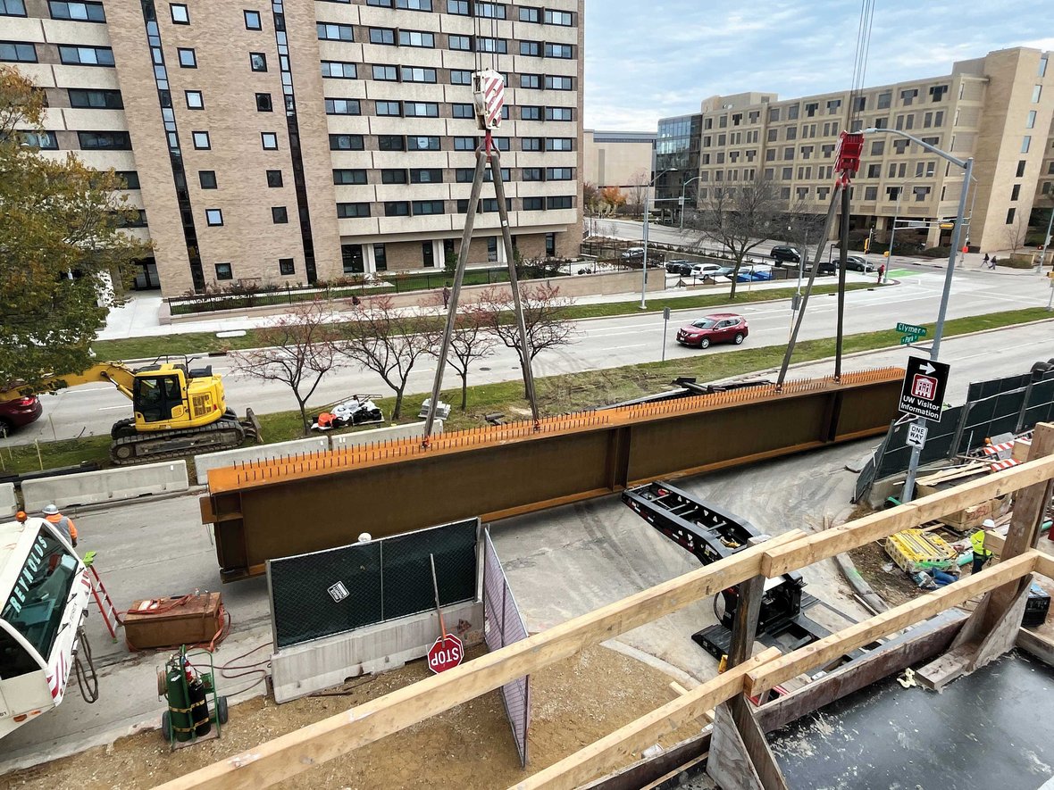 C.D. Smith crew coordinating dual crane operations on a closed-off street during early-morning girder placement at UW–Madison’s Levy Hall project site.