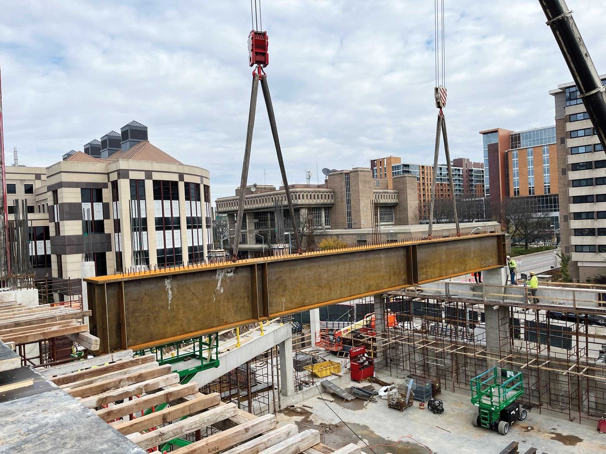 Ironworkers from C.D. Smith guide 78-foot steel girder into place with precision using dual cranes on a closed-off Madison street.