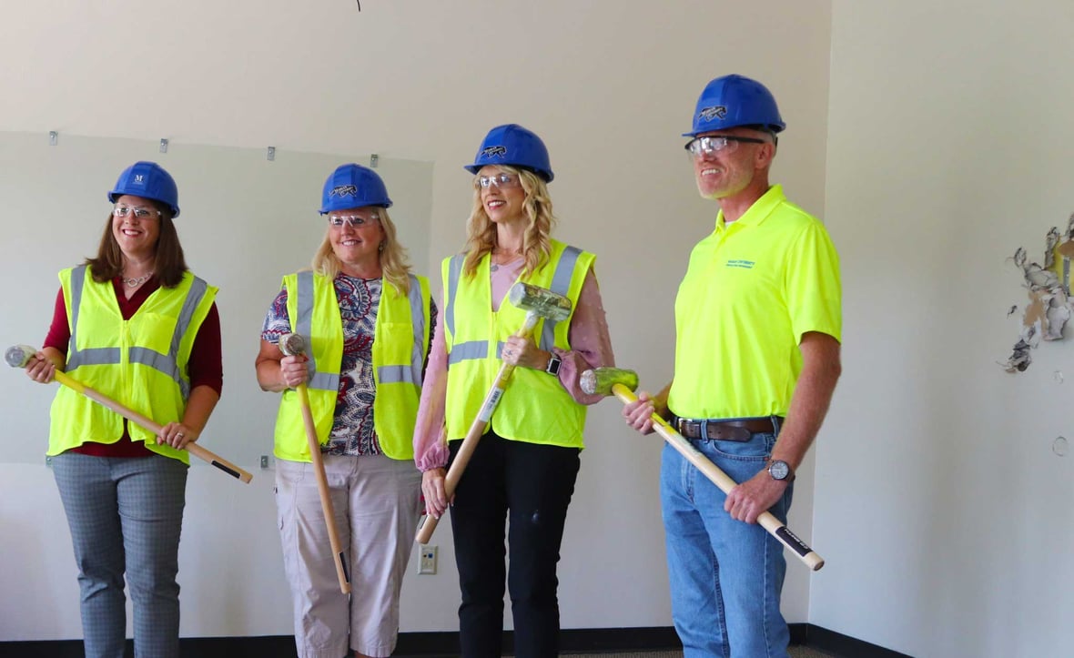Marian University Executives Faculty Students pose with sledgehammers for construction demolition bash celebration at new home of the Nursing Program