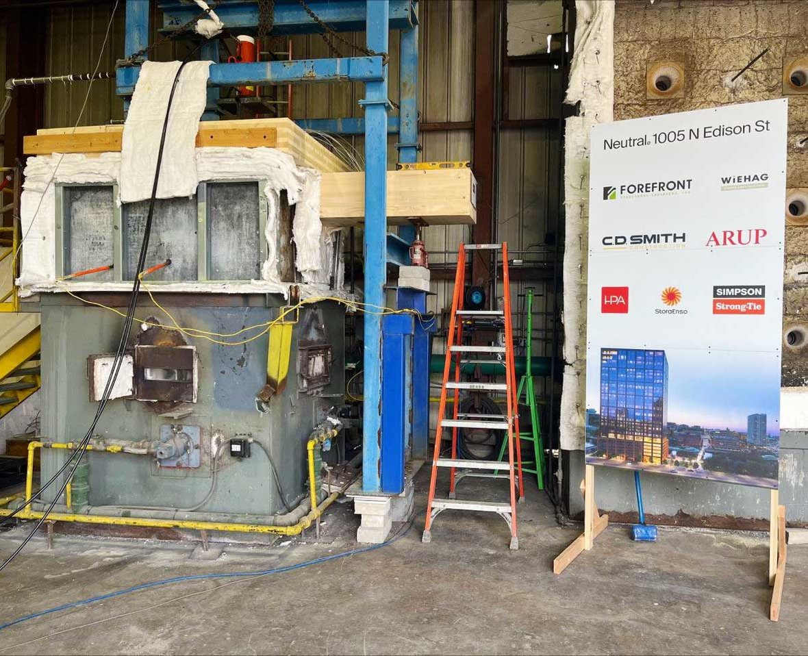 Mass timber fire resistance test setup at Southwest Research Institute showing glulam beam and cross-laminated timber (CLT) assembly with insulation and instrumentation, part of Wisconsin construction management efforts for sustainable high-rise building safety.