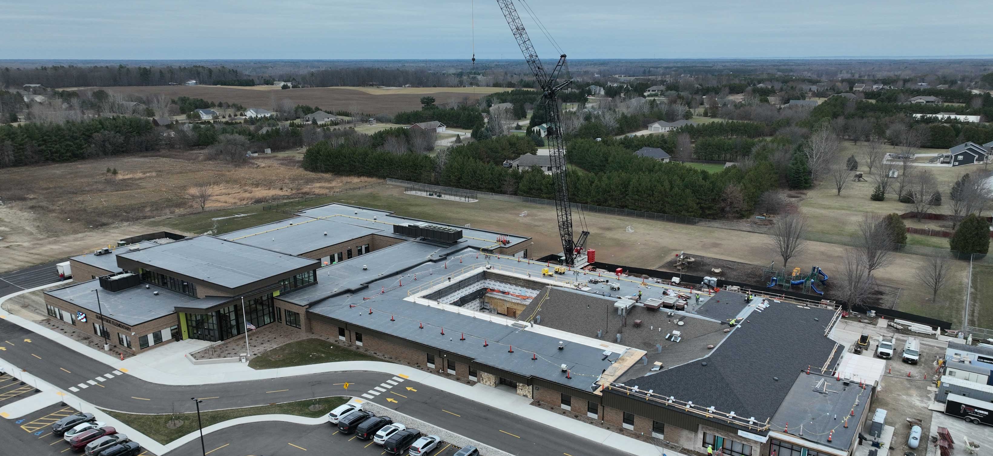 Aerial view of Sunnyside Elementary School during active construction showing crane operations and the addition taking shape alongside the existing building.