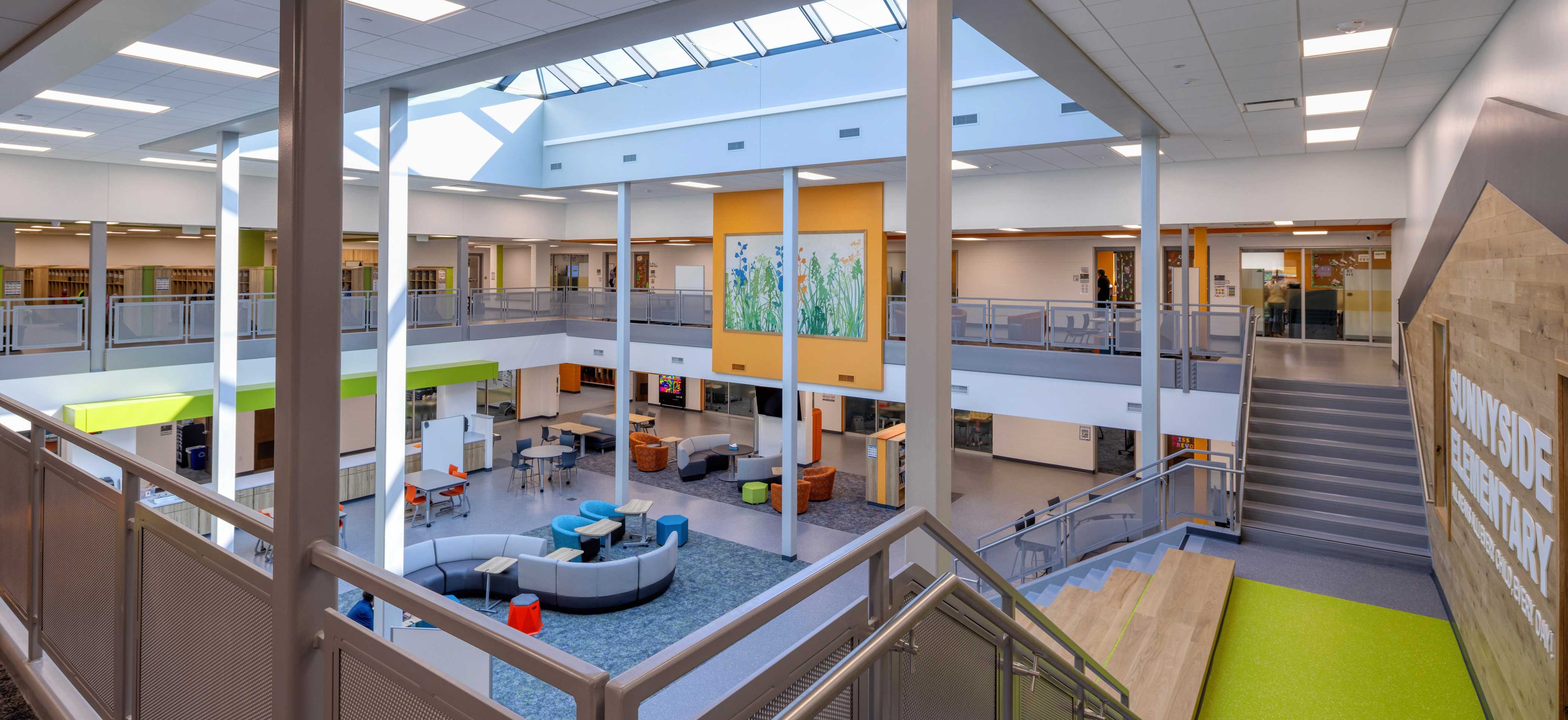Completed two-level Student Collaboration Hub at Sunnyside Elementary viewed from the upper level showing the central skylight and flexible learning spaces below.