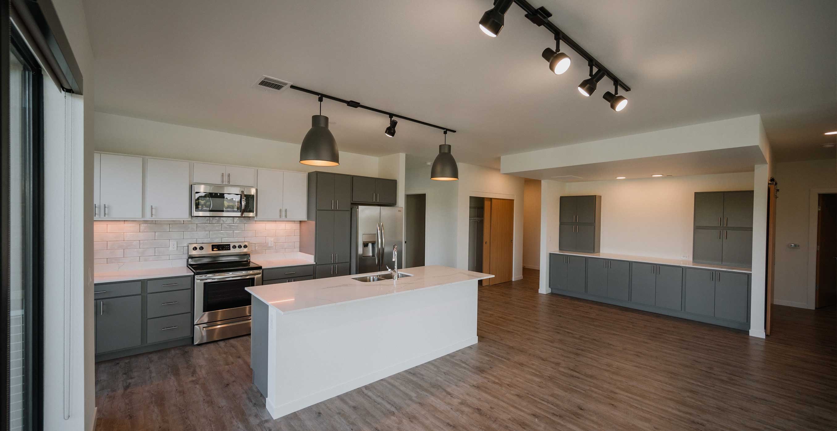 Open concept apartment kitchen at RiverHeath Willow with large island, stainless steel appliances, and modern cabinetry.