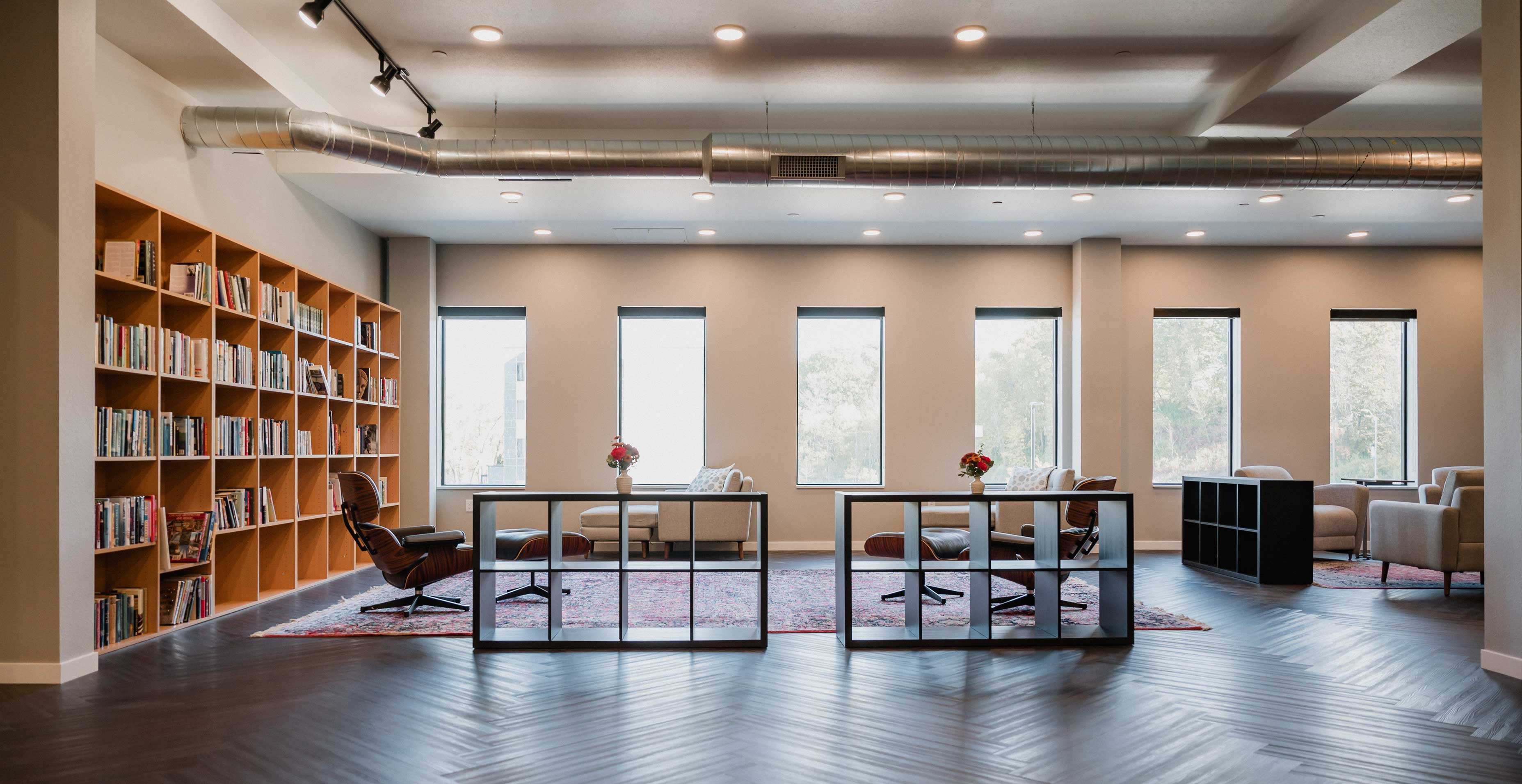 Library and game room at RiverHeath Willow featuring built in shelving, lounge seating, and natural light.