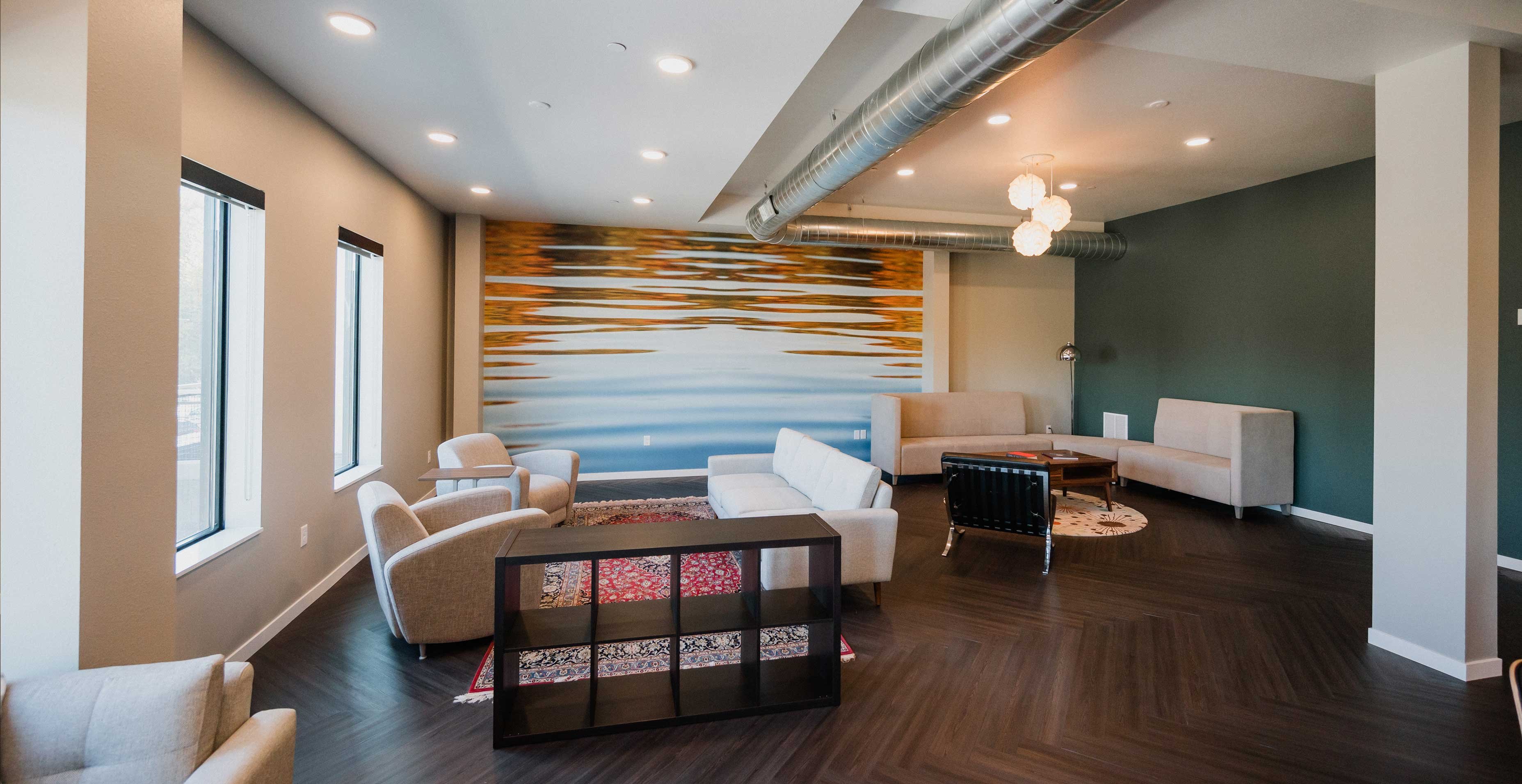 RiverHeath Willow community room with seating areas, accent wall mural, and contemporary lighting.