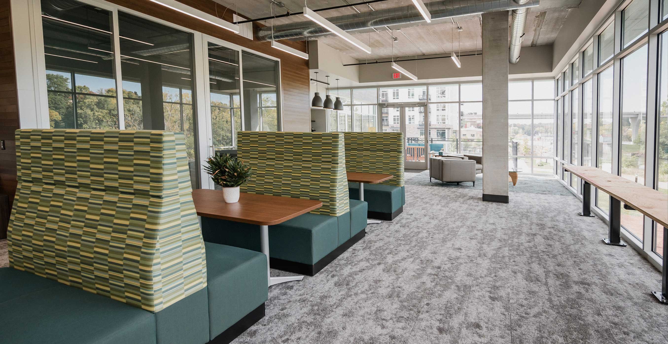 Amenity lounge at RiverHeath Willow with booth seating, large windows, and river views.