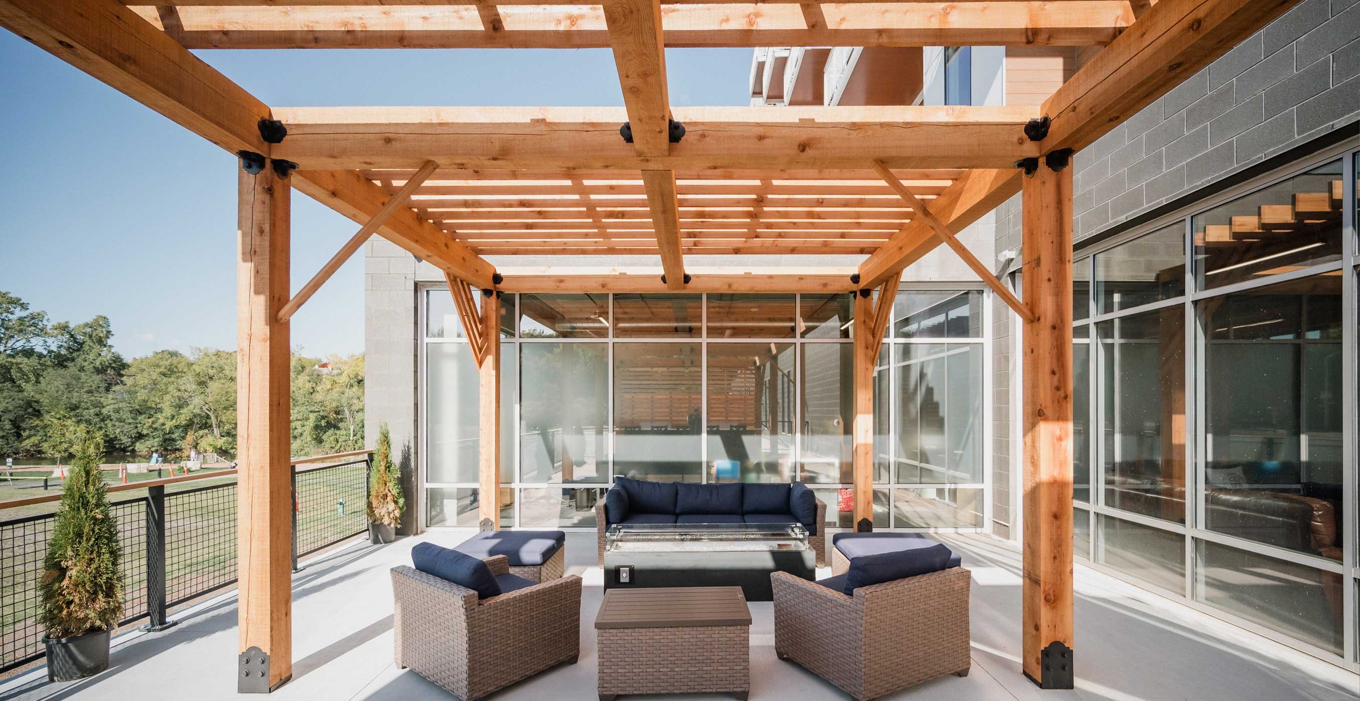 Outdoor terrace at RiverHeath Willow featuring wood pergola, lounge seating, and views of the riverfront setting.