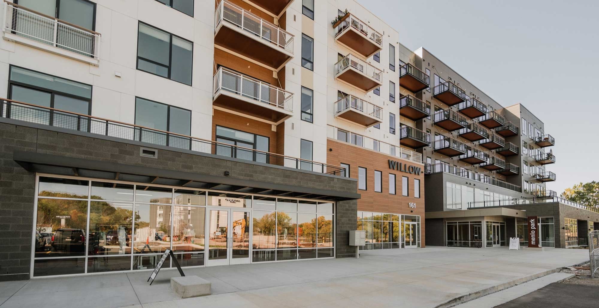 Street level retail storefronts at RiverHeath Willow with upper level multifamily housing and modern balcony design.