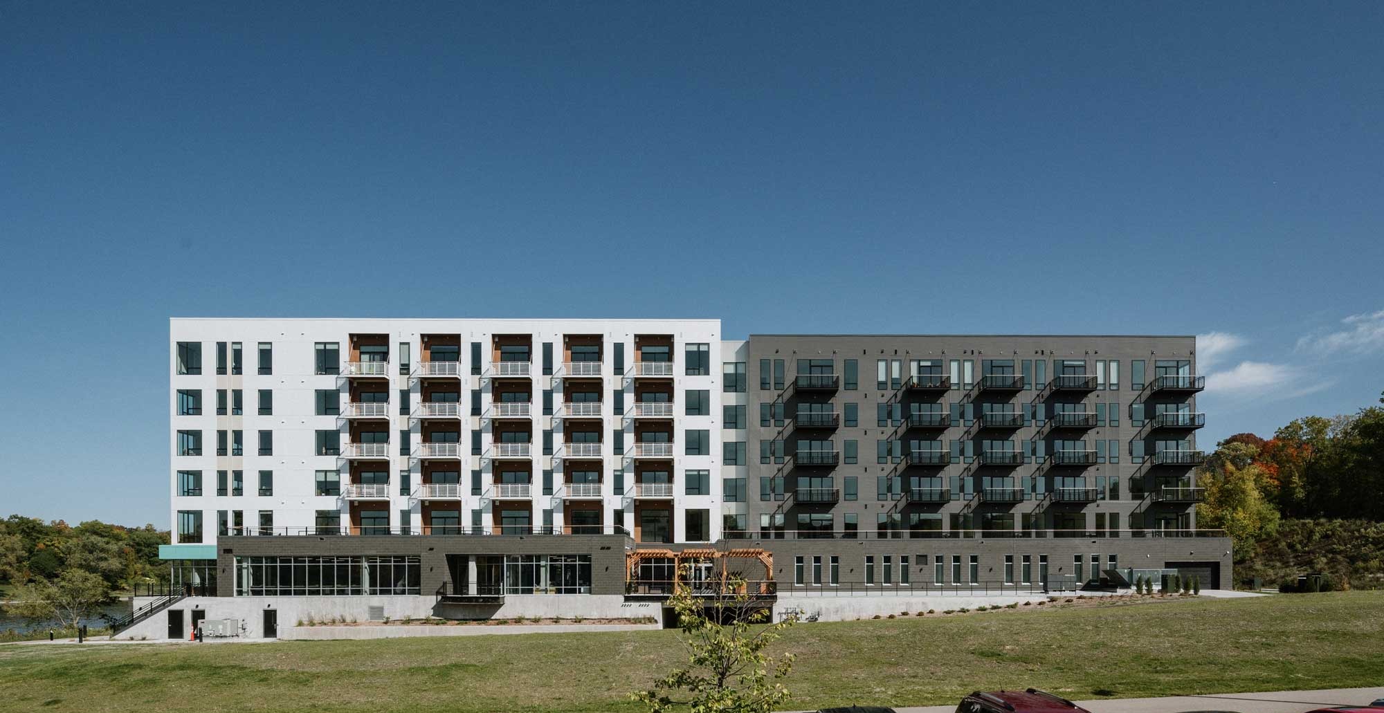 Full elevation of RiverHeath Willow mixed use development overlooking green space and riverfront setting.