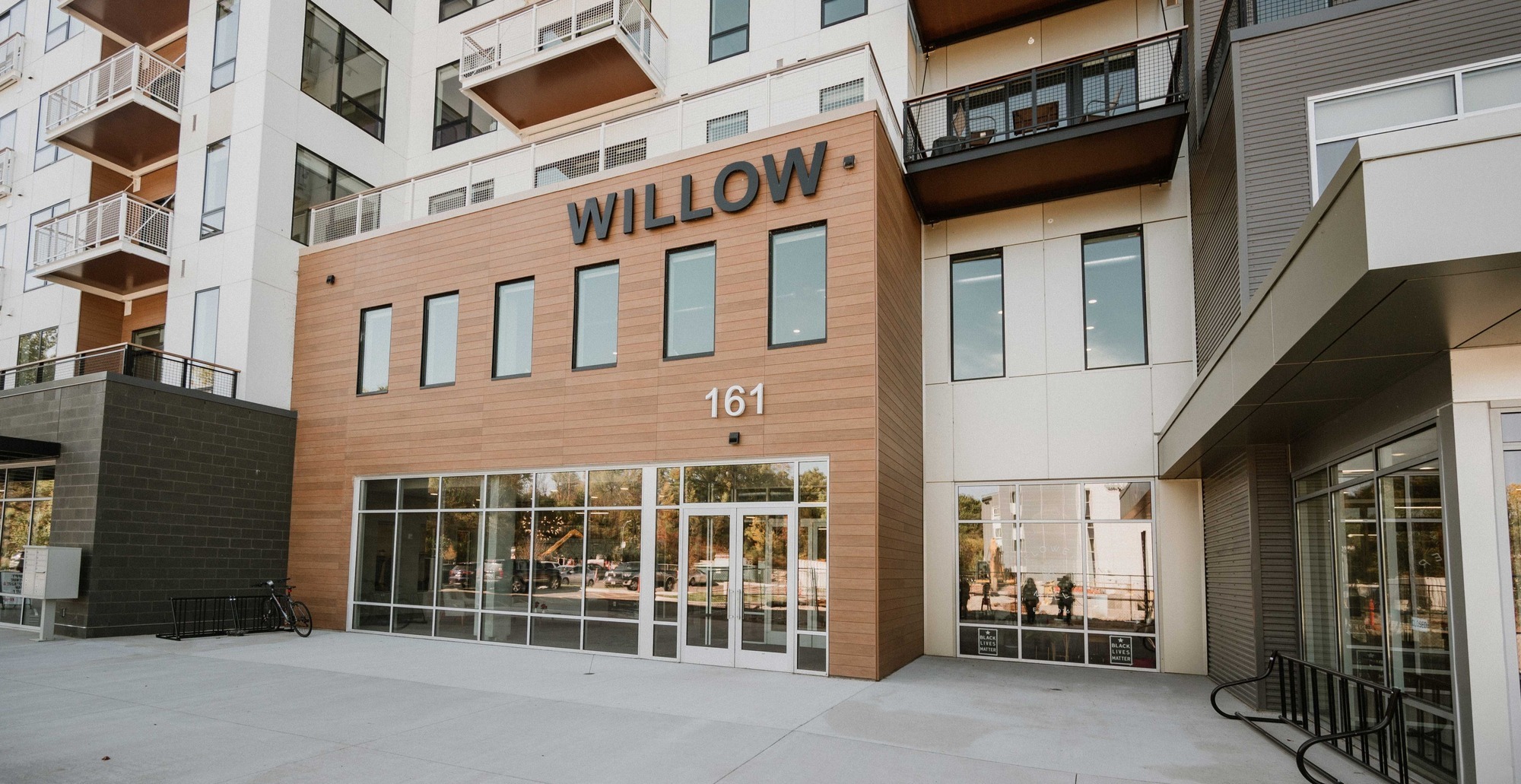 RiverHeath Willow residential entrance with WILLOW signage, street level storefront glass, and upper level apartment balconies.