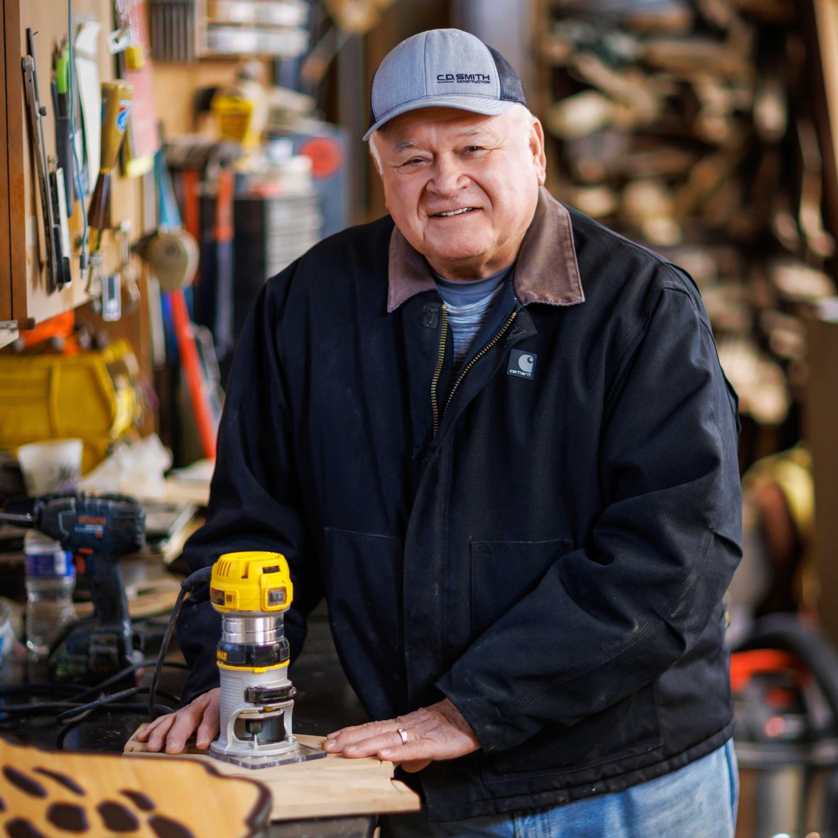 Arlyn Julka retired site superintendent CD Smith Construction with woodworking tools and woodshop in background