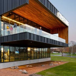 Exterior view of C.D. Smith Construction's corporate headquarters in Fond du Lac, WI, illuminated by lights at dusk. The building showcases modern architecture and integrated building solutions