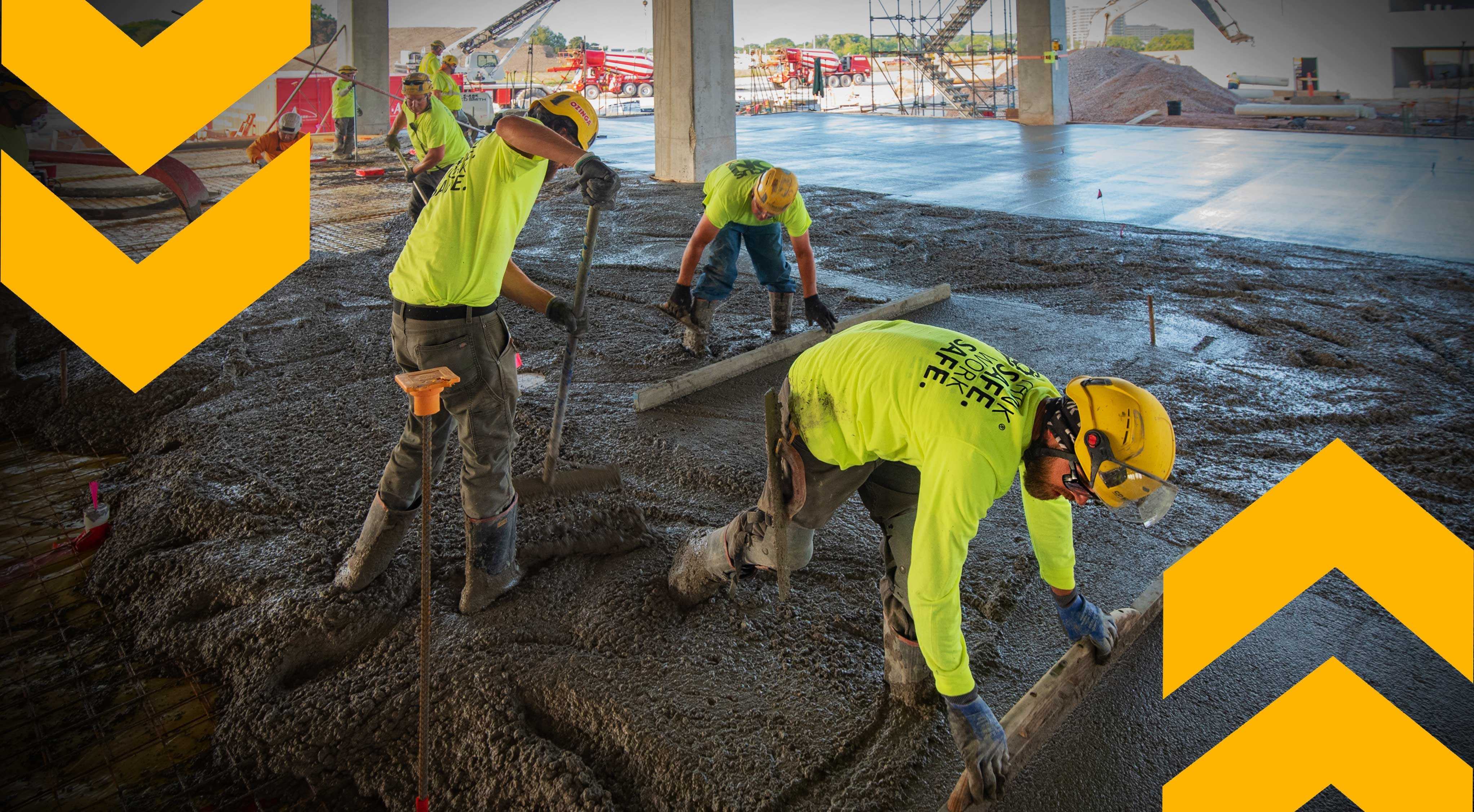 CD Smith Construction crew performing concrete skilled trades on commercial building site in Milwaukee Wisconsin - branded chevrons in foreground