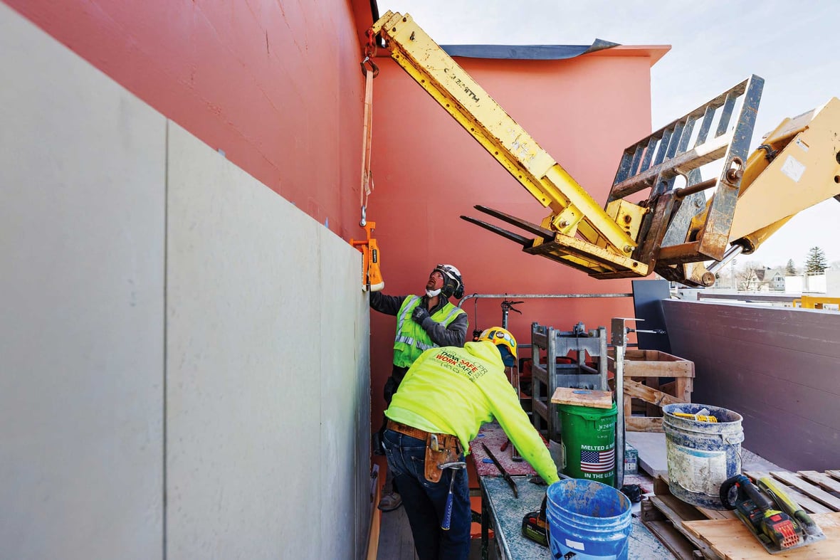 Masons from C.D. Smith Construction placing siding on the Kewaskum Community Building — a showcase of precision and pride in commercial masonry.