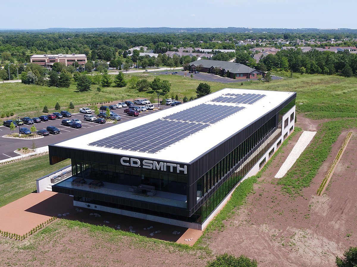 Aerial view of the C.D. Smith Corporate Office in Fond du Lac Wisconsin featuring rooftop solar panels and modern glass design built for energy efficiency and sustainability.